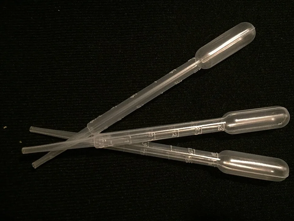 Graduated plastic transfer pipettes on a dark background